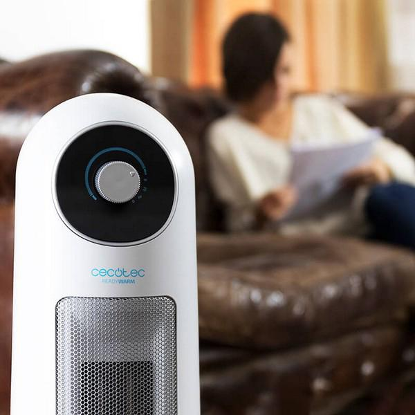 Biało-czarny grzejnik z przodu, a z tyłu kobieta czytająca na sofie.