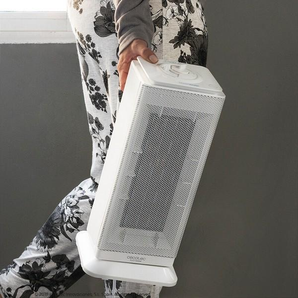 Osoba trzymająca biały grzejnik. Grzejnik ma siatkową przednią część i stoi na białej podstawie.