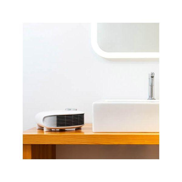 Biała i nowoczesna scena łazienkowa. Biały grzejnik na drewnianym stole obok umywalki.