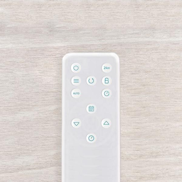 Biały pilot z wieloma przyciskami na drewnianej powierzchni. Przyciski są oznaczone.