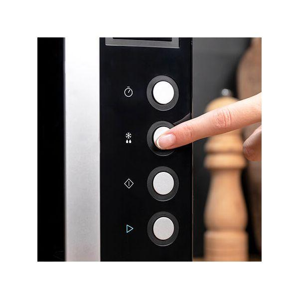 Zbliżenie panelu przycisków kuchenki mikrofalowej, palec naciska biały przycisk i drewniana solniczka.