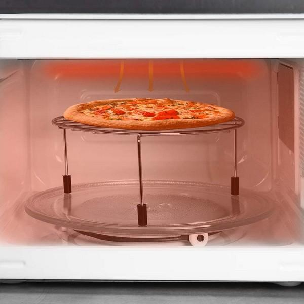 Pizza w kuchence mikrofalowej. Pizza na metalowym ruszcie w kuchence mikrofalowej. Czerwona poświata.