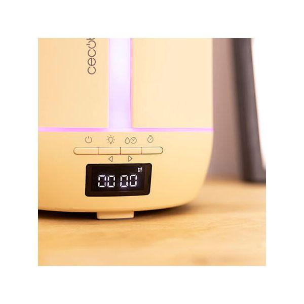 Kremowy nawilżacz z cyfrowym wyświetlaczem. Stoi na drewnianym stole. Przyciski są widoczne.