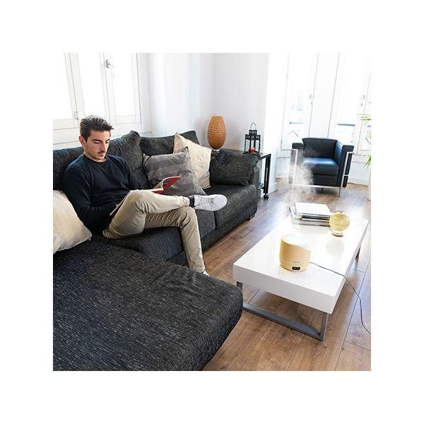 Mężczyzna na kanapie w salonie. W scenie znajduje się nawilżacz i biały stół.