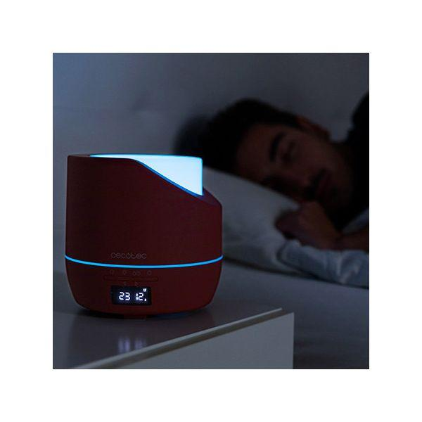 Czerwony dyfuzor z niebieskim światłem. Mężczyzna śpi w tle.