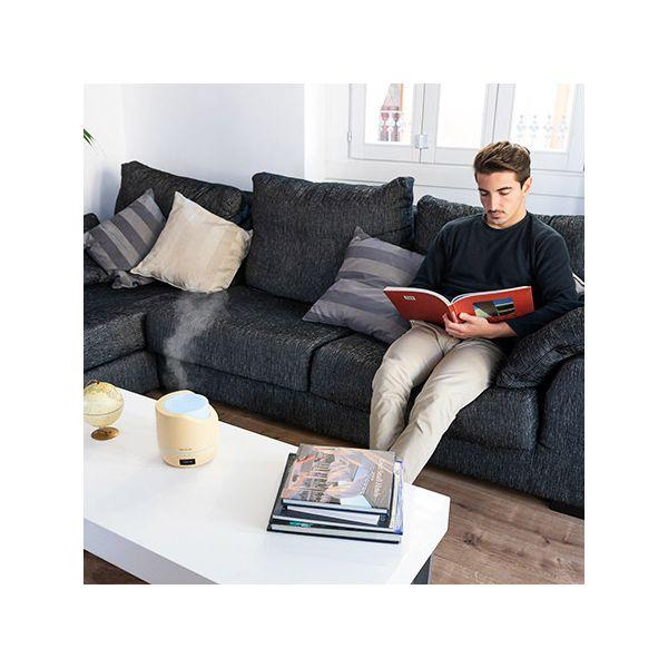 Mężczyzna czytający książkę, nawilżacz i książki na stoliku kawowym. Salon.