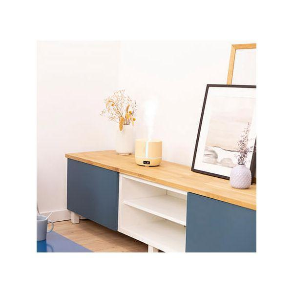 Drewniana komoda z dyfuzorem. Wazon z suszonymi kwiatami, ramka na zdjęcia. Biała ściana.