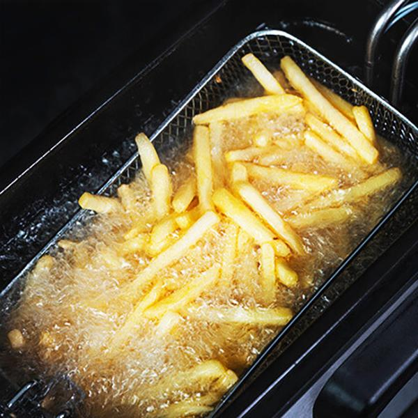 Frytki w koszu do smażenia zanurzone w gorącym oleju, złote i bulgoczące.