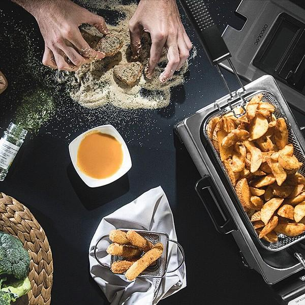 Osoba panieruje niektóre produkty spożywcze, z frytownicą i smażonym jedzeniem widocznym na scenie.