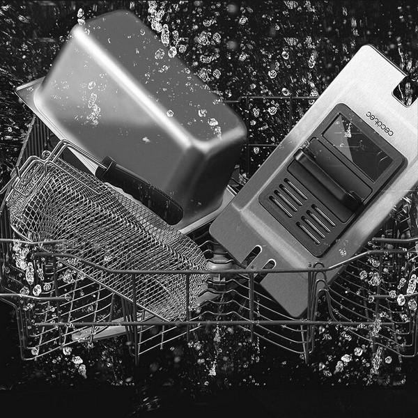 Zawartość zmywarki. Zawiera metalowy kosz, tacę i inne przedmioty kuchenne. Widoczne krople wody.