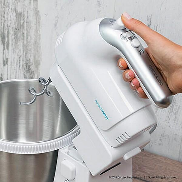 Weißer Handmixer in Gebrauch, Metallschüssel und Mixkopf, Hand hält Einschaltknopf.