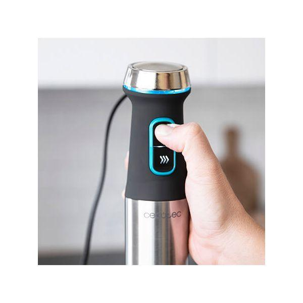 Dłoń trzymająca czarny i srebrny blender ręczny z niebieskim przyciskiem.