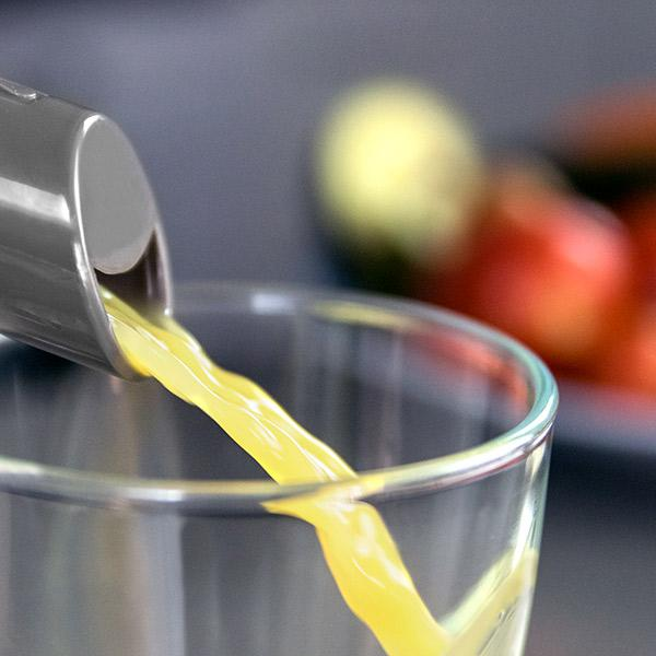 Liquido giallo versato in un bicchiere. Lo sfondo è sfocato.