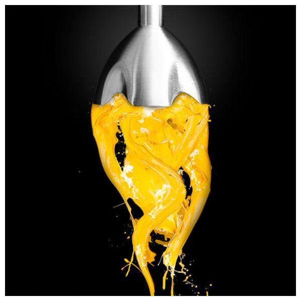 Obiekt ze stali nierdzewnej wylewający żółtą farbę. Farba spływa w dół w postaci rozprysku.