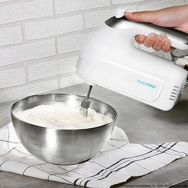 Ein weißer Handmixer verrührt Schlagsahne in einer Edelstahlschüssel.