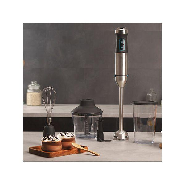Stafmixer met accessoires op een aanrecht. Er is een garde, een hakkom en een beker.