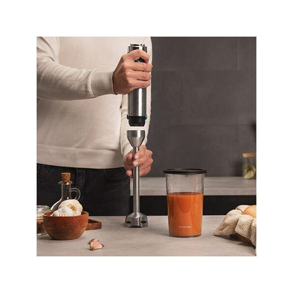 Een persoon mixt een drankje met een blender. Er staan andere dingen op tafel.