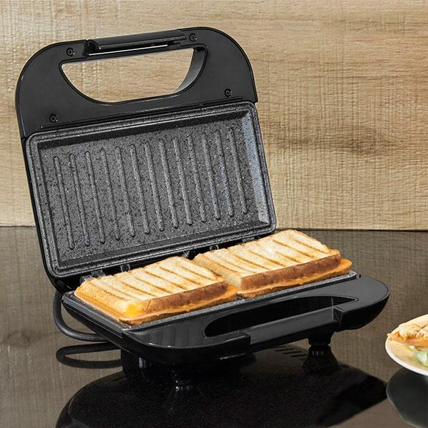 Macchina per sandwich con due panini tostati all'interno. Sfondo in legno.