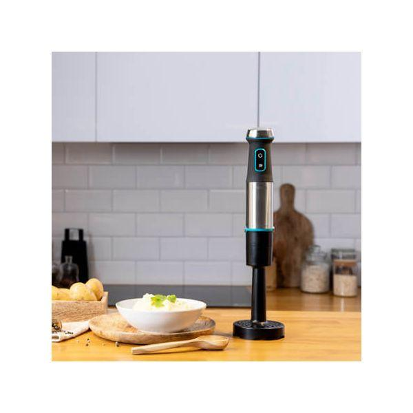 Stafmixer met een kom aardappelpuree en een houten lepel op een houten tafel.