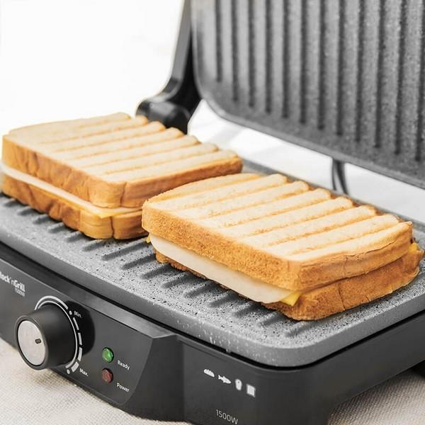 Dwie tosty na czarno-szarym grillu. Kanapki są cięte po przekątnej, widoczny ser w środku.