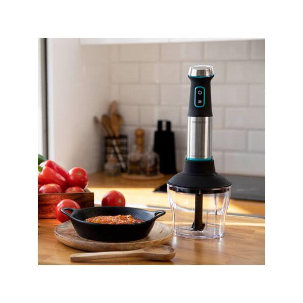 Een blender en ingrediënten staan op een houten tafel. Tomaten in een houten kist en een schaal met saus.