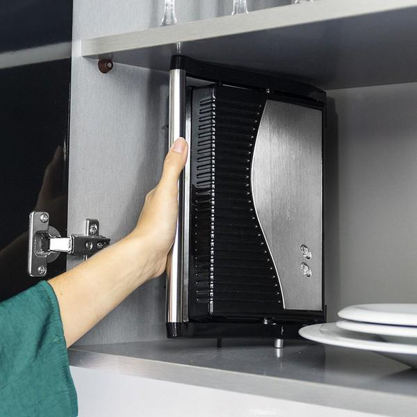 Ręka otwiera srebrne urządzenie w szafce. Urządzenie jest czarne i srebrne.