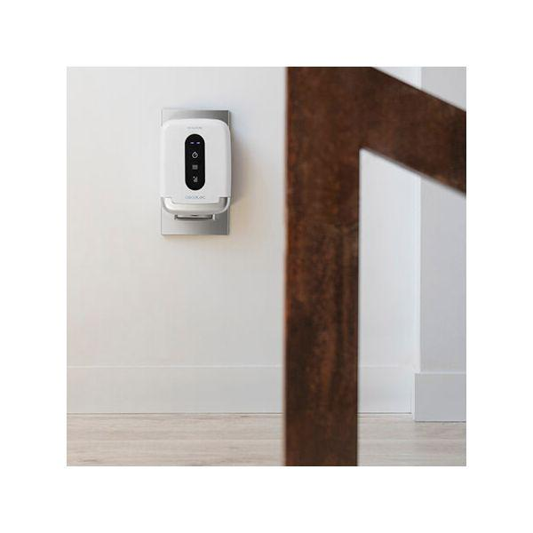 Un dispositivo blanco montado en la pared con botones negros y una base plateada está en una pared blanca. Una viga marrón está cerca.