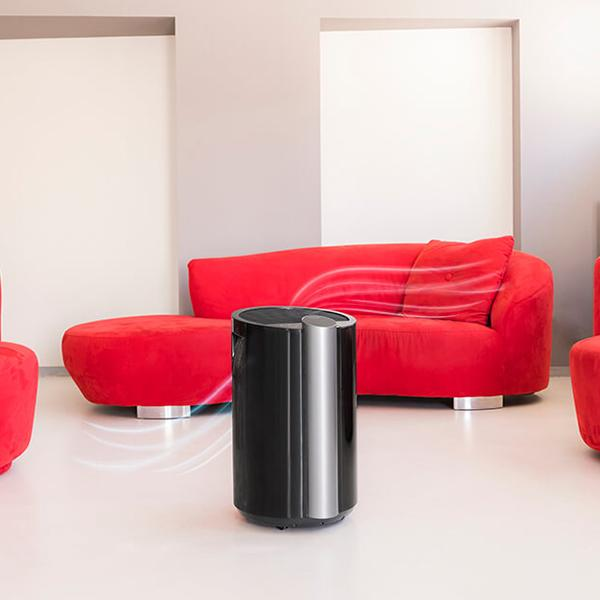 Oczyszczacz powietrza we wnętrzu. Czerwona sofa w tle, z zakrzywionymi liniami przepływu powietrza.