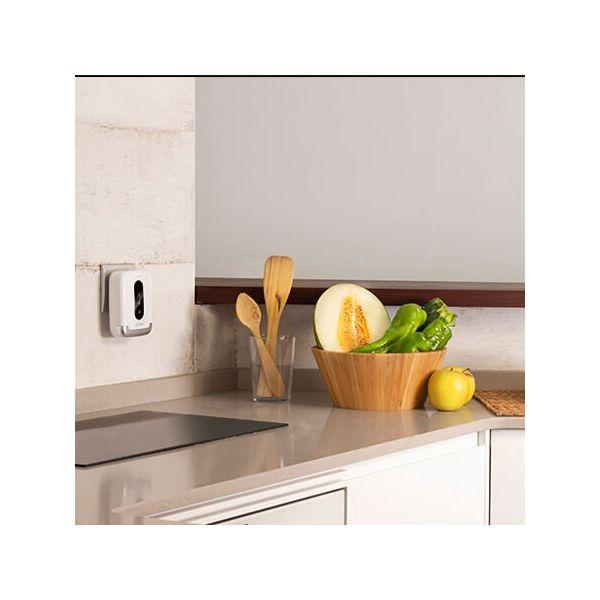 Escena de cocina con un dispensador y un cuenco de verduras en una encimera.
