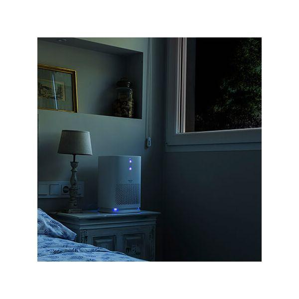 Purificatore d'aria su un comodino in camera da letto. Sono visibili una lampada e una finestra.
