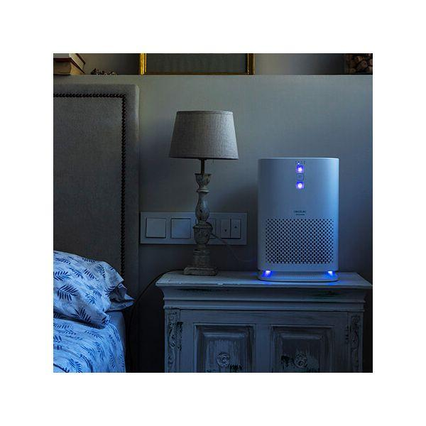 Purificatore d'aria su comodino, lampada e letto in una stanza buia.