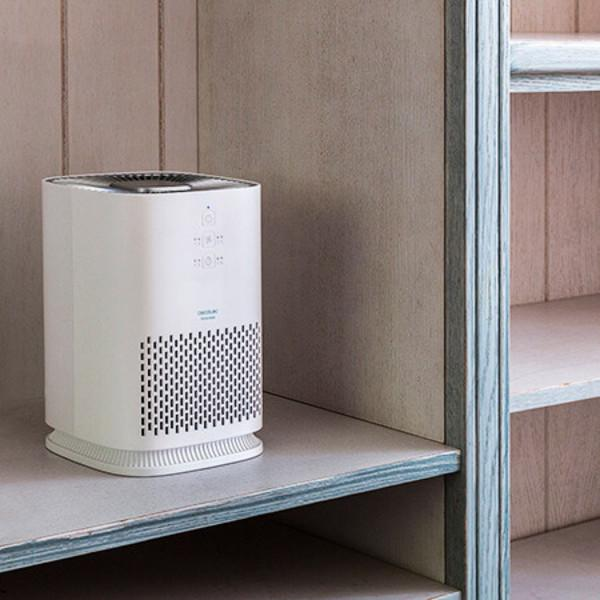 Purificatore d'aria bianco all'interno di un armadio. Ha una griglia frontale e un pannello superiore.