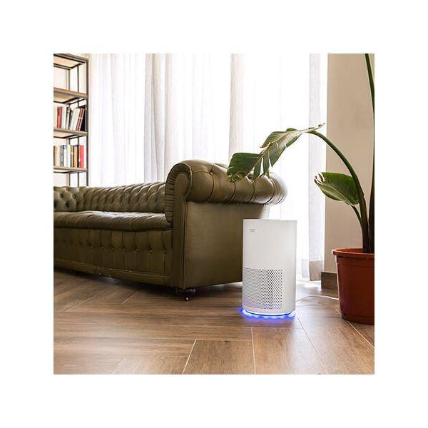 Soggiorno con divano verde, purificatore d'aria bianco e libreria.