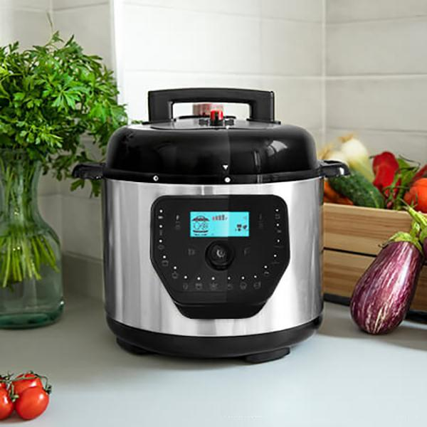 Una olla a presión plateada y negra con pantalla digital y verduras.