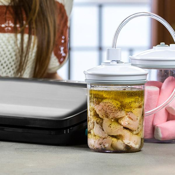 Słoik z jedzeniem w słoiku z innymi przedmiotami obok. Jedzenie jest konserwowane w oleju.