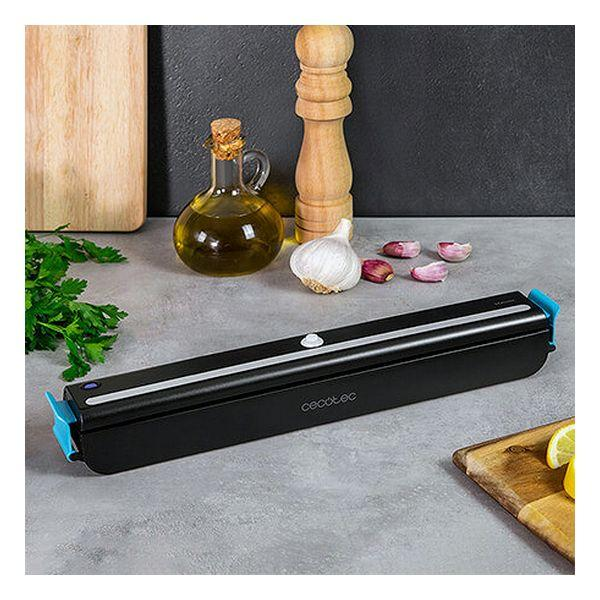 Sellador al vacío negro con extremos azules sobre una encimera de cocina, rodeado de ingredientes.
