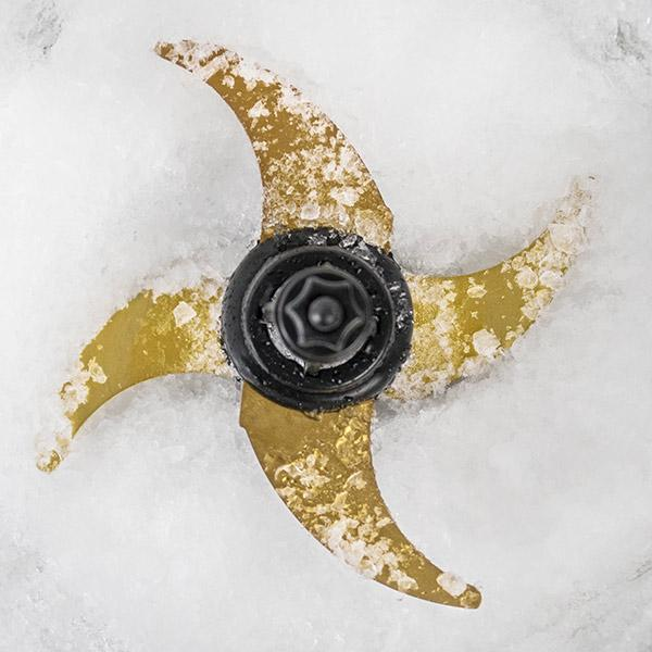 Ein vierflügeliges Mixermesser bedeckt mit Eiskristallen, auf einer weißen Oberfläche.