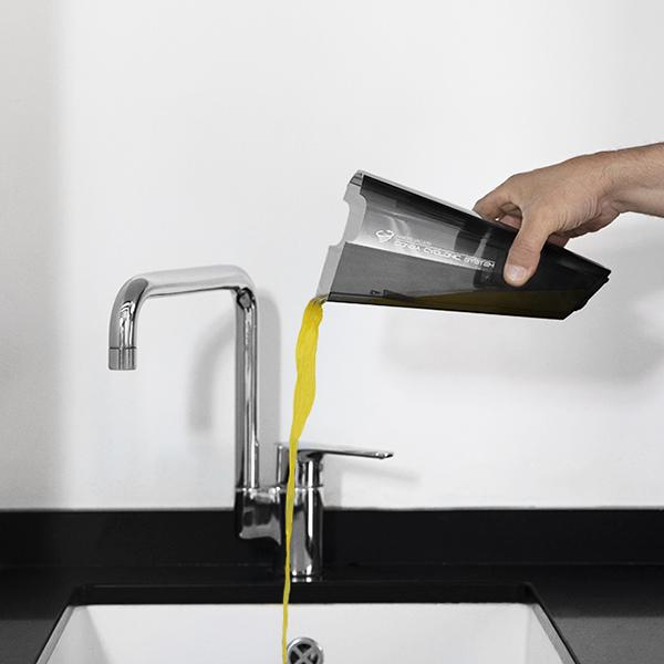 Persona vertiendo líquido amarillo de un recipiente en un fregadero. Grifo de acero inoxidable.