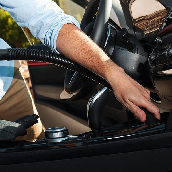 Une personne qui passe l'aspirateur dans l'intérieur d'une voiture avec un aspirateur.