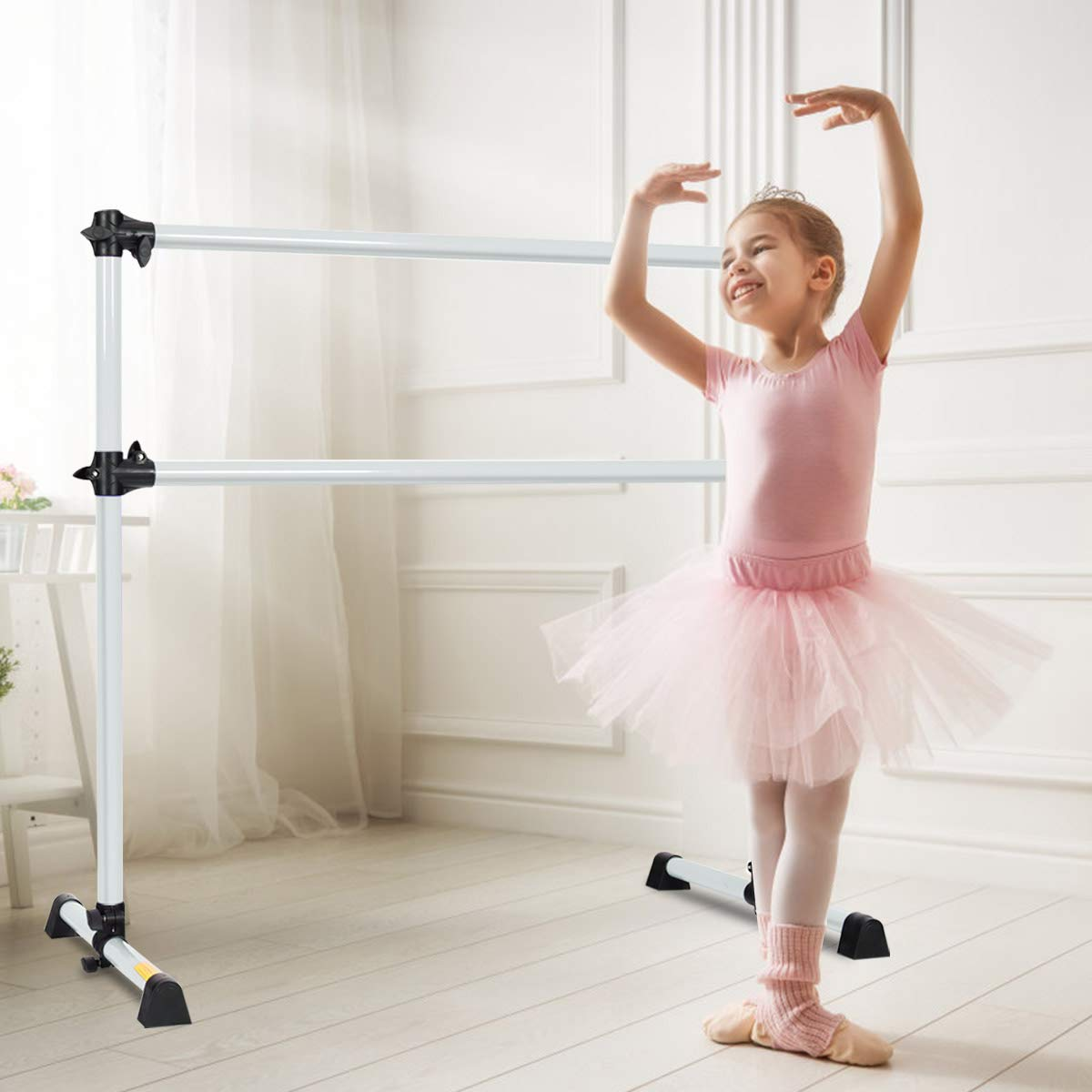 Junges Mädchen in rosa Tutu an Ballettstange. Weißer Raum mit transparenten Vorhängen.
