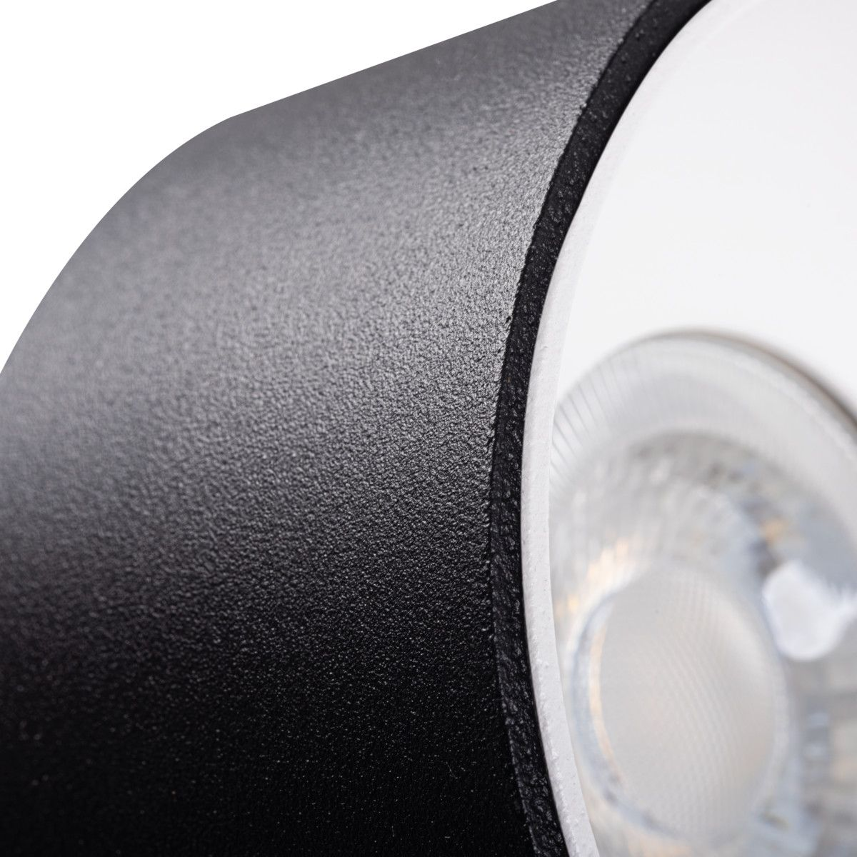 Primo piano di un apparecchio di illuminazione in bianco e nero con superficie strutturata e luce brillante.