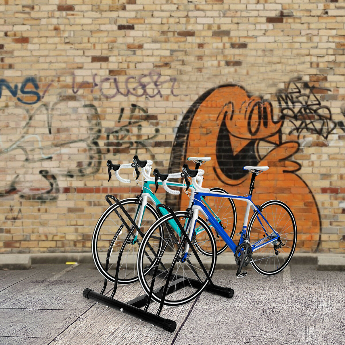 Zwei Fahrräder in einem Fahrradständer an einer Backsteinmauer mit Graffiti.