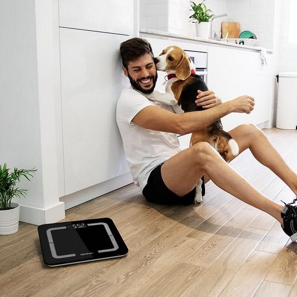 Mężczyzna i pies siedzący na podłodze z wagą na pierwszym planie.