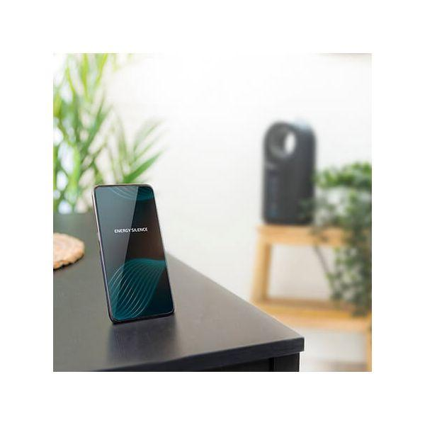 Telefon na ciemnym stole wyświetla tekst: ENERGY SILENCE. W tle mały oczyszczacz powietrza.