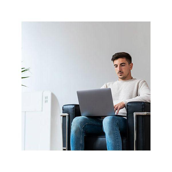 Mężczyzna siedzący, używający laptopa na kolanach.