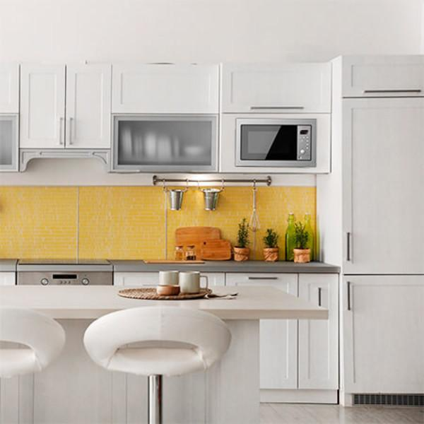 Biała kuchnia z żółtą mozaiką, białymi szafkami i barem.