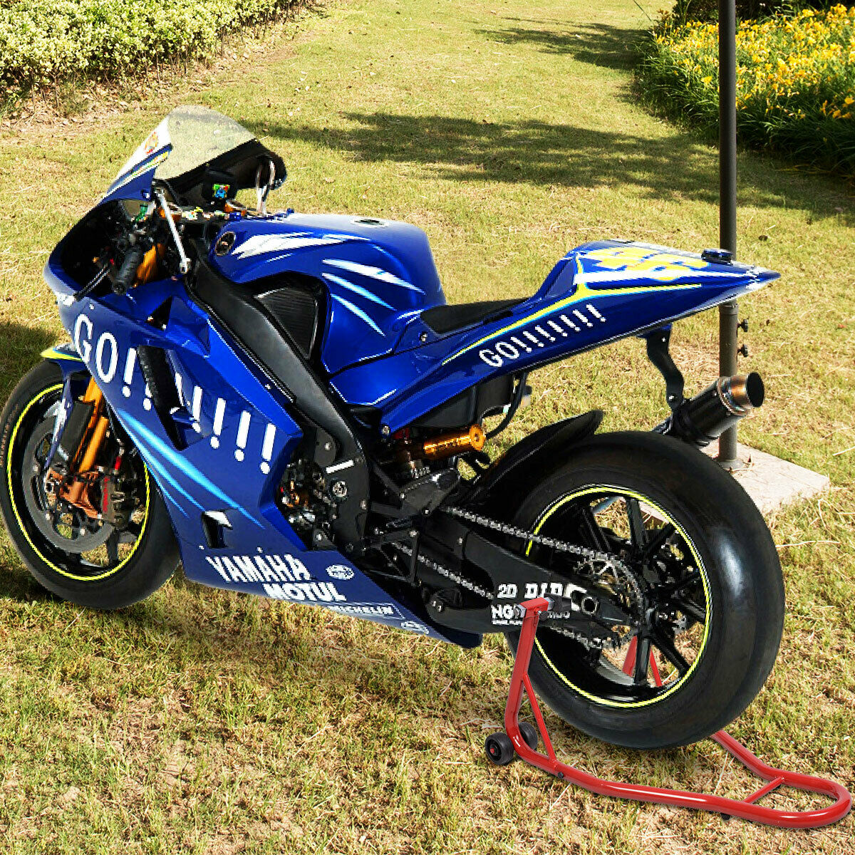 Ein blaues Yamaha-Motorrad auf einem Ständer, auf einer Wiese, Seitenansicht.