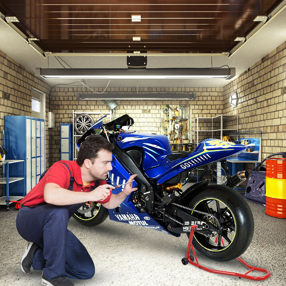 Mechaniker arbeitet in einer Garage an einem blauen Motorrad.