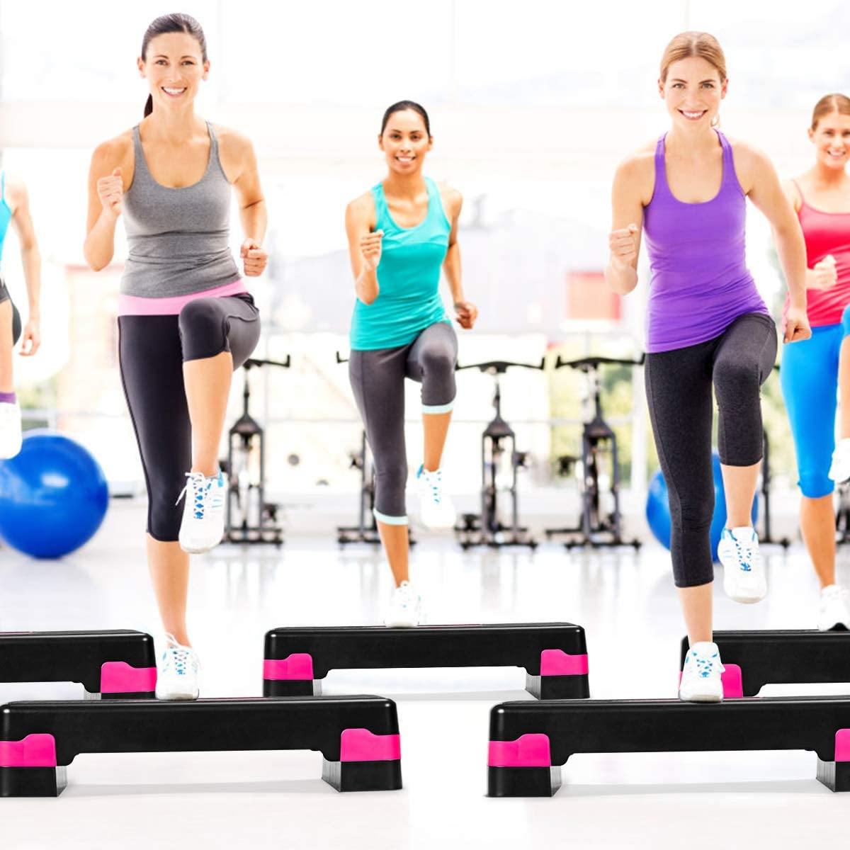 Gruppe von Frauen, die in einem Fitnessstudio auf Trittplattformen trainieren.