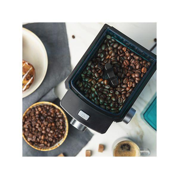 Ziarna kawy w pojemniku, z miską ziaren i filiżanką kawy z boku.